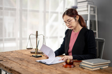 A woman in a black suit is sitting at a desk with a stack of books