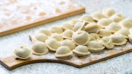 Homemade dumplings close-up. handmade dumplings on a wooden board, selective focus, tinted image, traditional Russian dish,