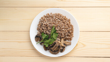 Buckwheat porridge with fried mushrooms on a plate on a wooden background. Healthy diet food. The concept of healthy eating