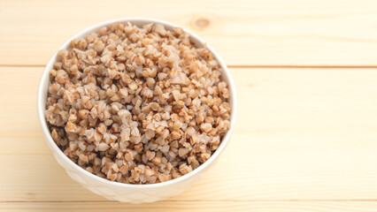 buckwheat porridge in a round white plate on a wooden table.