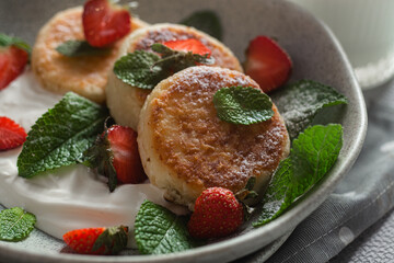 Homemade cottage cheese pancakes with sauce and strawberries. syrniki