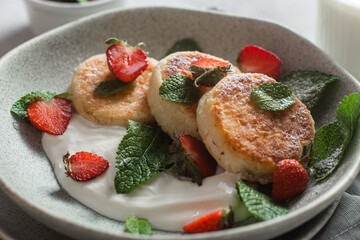 Homemade cottage cheese pancakes with sauce and strawberries. syrniki