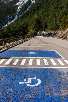 A designated handicapped parking space with a blue and white symbol, nestled in a scenic mountainous road setting