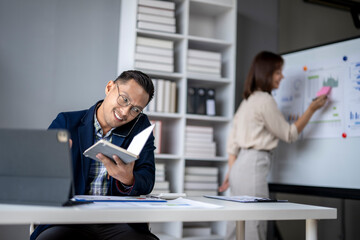 A man is sitting at a desk with a book in front of him