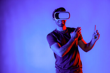 Caucasian man wearing virtual reality goggle while standing at neon light background. Person with...