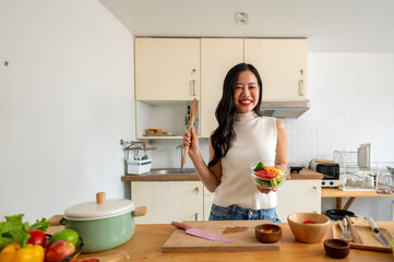 A woman is smiling and holding a bowl of food in a kitchen