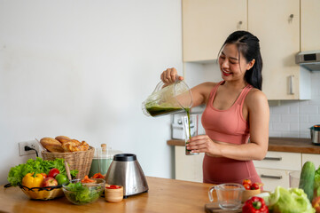 A woman is making a green smoothie in a kitchen