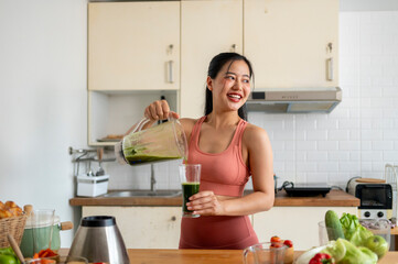 A woman is making a green smoothie in a kitchen