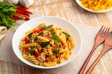 Stir fried trivelle pasta with Canned tuna fish and crispy basil leaves in white plate,Spicy pasta Pad Kra Pao.Thai fusion food