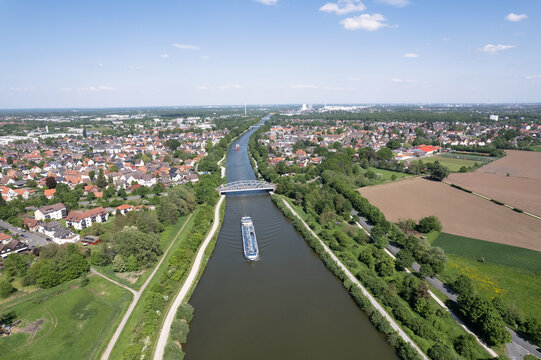 A river flows through an urban landscape with a boat sailing under a cloudy sky 5k Drone view Hanover Seelze Germany 
