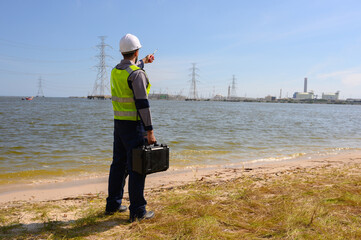 Front view of engineer standing holding tool back and communicating with the team via walkie-talkie