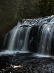 Silky white long exposure shot of idyllic Coal Creek Falls river waterfall flowing in Runanga Greymouth New Zealand