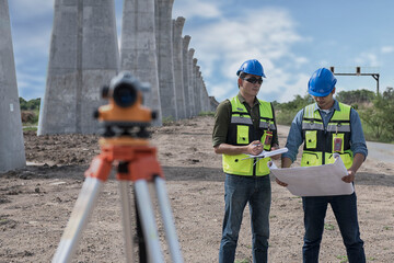 construction workers at work.  surveyor in green work clothes and helmet talking produces calculations on drawing.