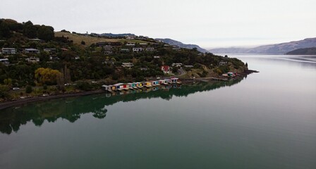Historic colorful wooden boat sheds on Duvauchelle Bay shore in Akaroa Harbour, Banks Peninsula,...