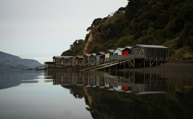 Historic colorful wooden boat sheds on Duvauchelle Bay shore in Akaroa Harbour, Banks Peninsula,...