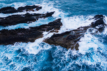 Waters of the ocean, swirl around the rocky and scenic coastline. Sea waves breaking over rocks