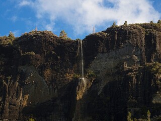Naklejka premium Small waterfall river water dropping off cliff edge Kaiaraara Rocks Dukes Nose, Whangaroa harbour Northland New Zealand