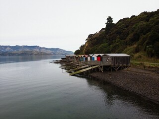 Historic colorful wooden boat sheds on Duvauchelle Bay shore in Akaroa Harbour, Banks Peninsula, Canterbury, New Zealand