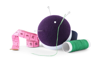 Pincushion, sewing needles, pins, spool of thread and measuring tape isolated on white