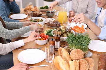 Friends eating vegetarian food at wooden table indoors, closeup