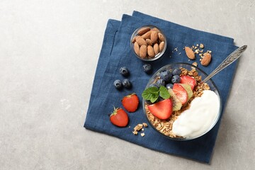 Tasty granola with berries, yogurt and mint on grey table, top view. Space for text