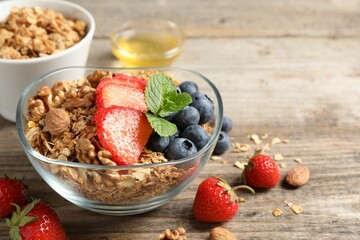 Tasty granola with berries, nuts and mint on wooden table. Space for text