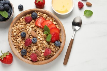 Tasty granola with berries, nuts and mint on white table, flat lay