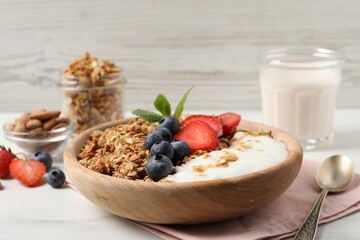 Tasty granola with berries and yogurt in bowl on white table, closeup