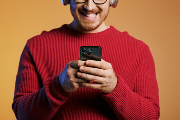 Stylish man in headphones captivated by cell phone screen.