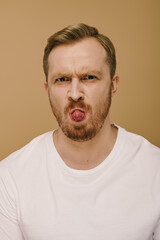 Handsome man in stylish attire making a silly face by sticking out his tongue.