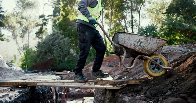 Construction site, outdoor and man with wheelbarrow for materials, cement and concrete mixing. Industrial excavation, male contractor or builder with transport for gravel, soil and renovation items
