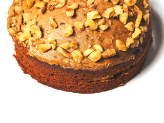 A nutty looking cake with nuts on top. The cake is brown and has a nutty flavor. Bakery high quality product. White background. Special sweeet treat.