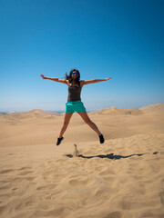 Obraz premium Peruvian Woman Wears a Blue Short Jumps Front the Camera in Huacachina Desert in Ica Peru