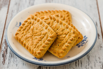 Array of biscuits neatly arranged on a plate, on white wooden table.