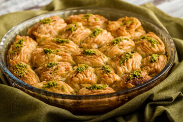 Turkish pistachio pastry dessert, Baklava on a round tray with dramatic lighting.