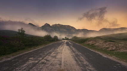 Naklejka premium carretera de montaña en primer plano nos guía hacia los montes del fondo en Lunada, Burgos