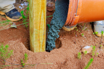 Newly installed timber fencing wooden fence posts are poured with concrete