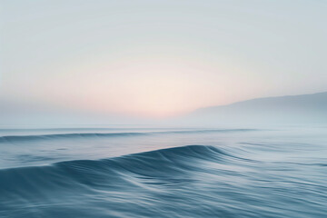 Obraz premium Calm ocean waves at dawn under a serene pastel sky with misty mountains in the background, creating a tranquil and peaceful early morning seascape perfect for relaxation and meditation 