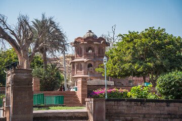 Ancient Indian Temples of structure featuring intricate carvings and vibrant floral foreground, Mandore Gardens, Jodhpur, Rajasthan, India