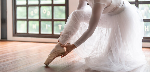 Ballerina in ballet shoes. Asian girl tying ribbons of toe shoes. ballet dancer preparing and wearing ballet shoes in dance studio prepares for a rehearsal.