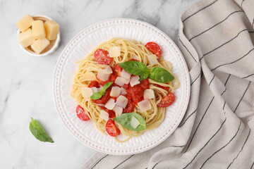 Tasty pasta with tomato sauce, cheese and basil on white marble table, flat lay