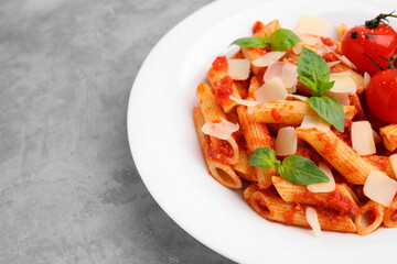 Tasty pasta with tomato sauce, cheese and basil on grey table, space for text