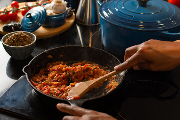 Close-up of a woman's hands in the kitchen making delicious tomato sauce using a frying pan at home