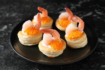 Delicious puff pastry with shrimps, cream cheese and red caviar on dark table