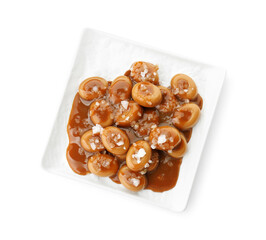 Plate with tasty candies, caramel sauce and salt isolated on white, top view