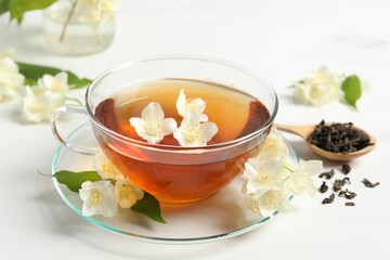 Hot jasmine tea in cup and flowers on white marble table