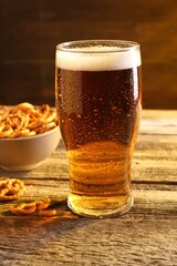 Glass of beer and pretzel crackers on wooden table