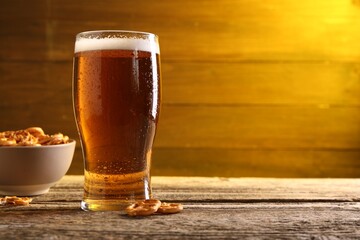 Glass of beer and pretzel crackers on wooden table, space for text