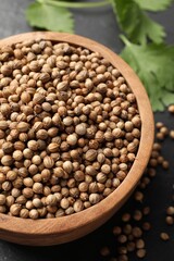 Dried coriander seeds in bowl on gray table, closeup