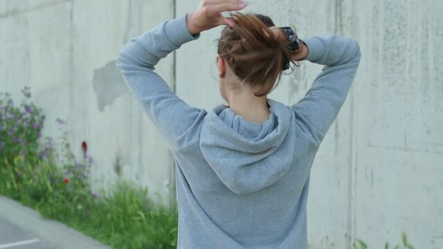 A young woman is tying her hair back